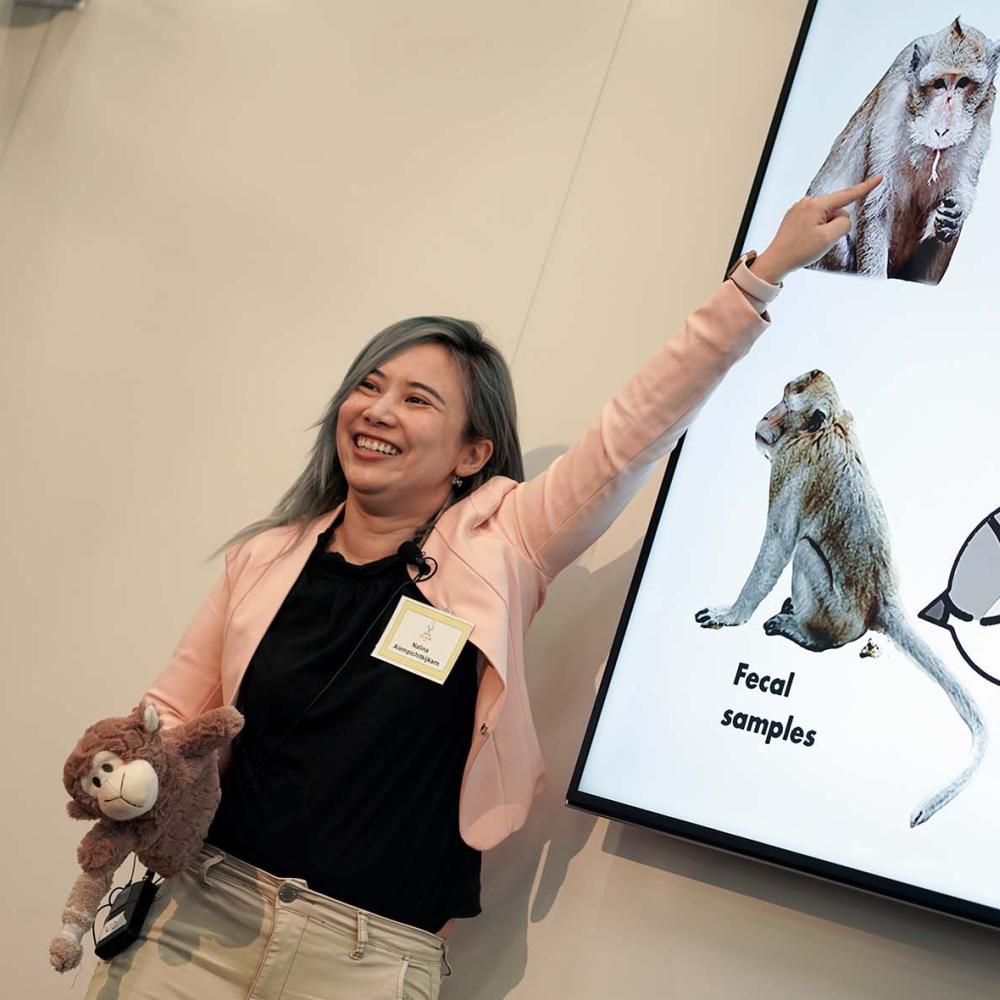 Student with plush monkey points to PowerPoint presentation.